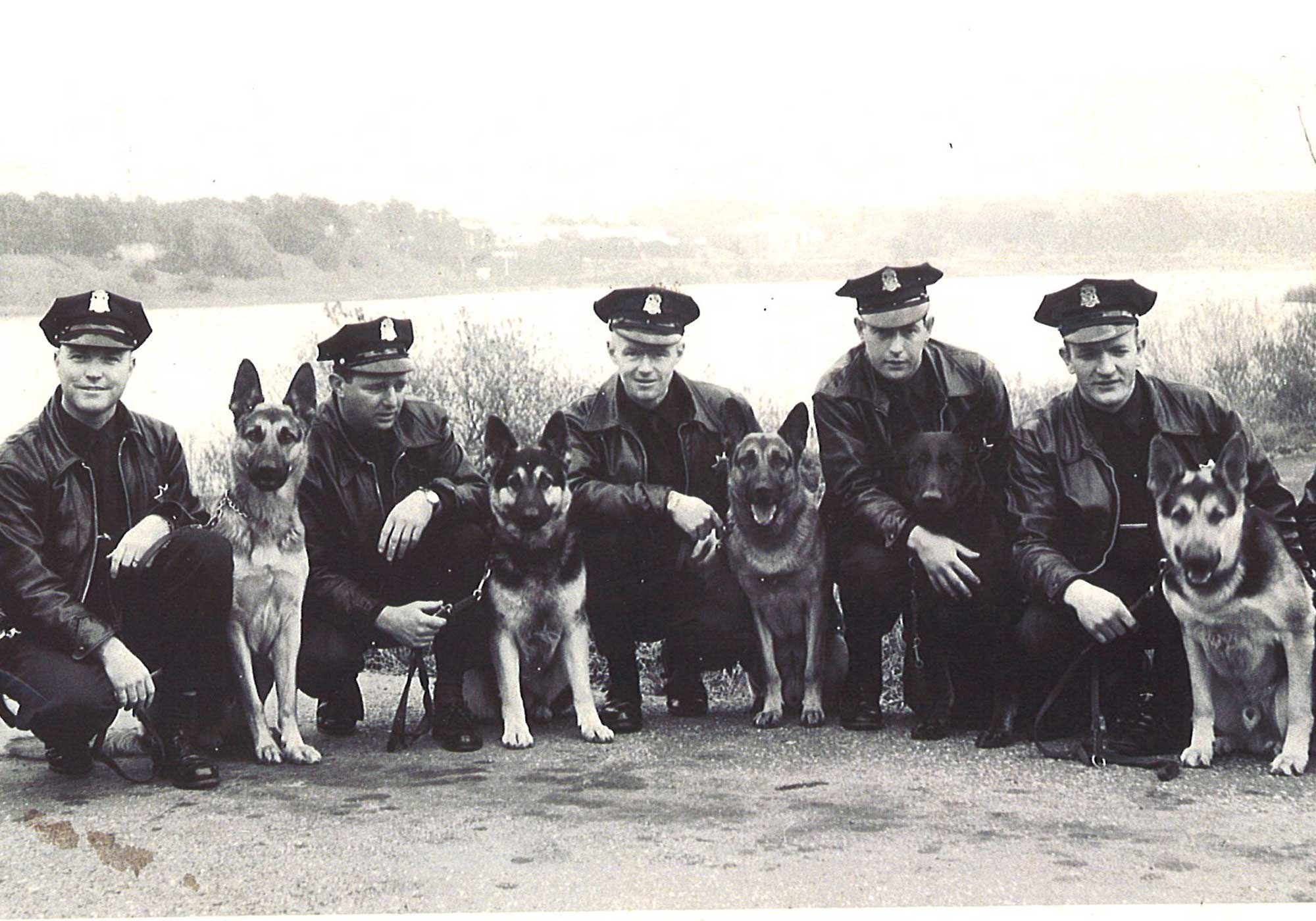 Group of police men kneeling next to their k-9. 