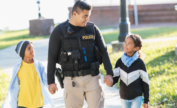 police officer walking with two young children holding hands 