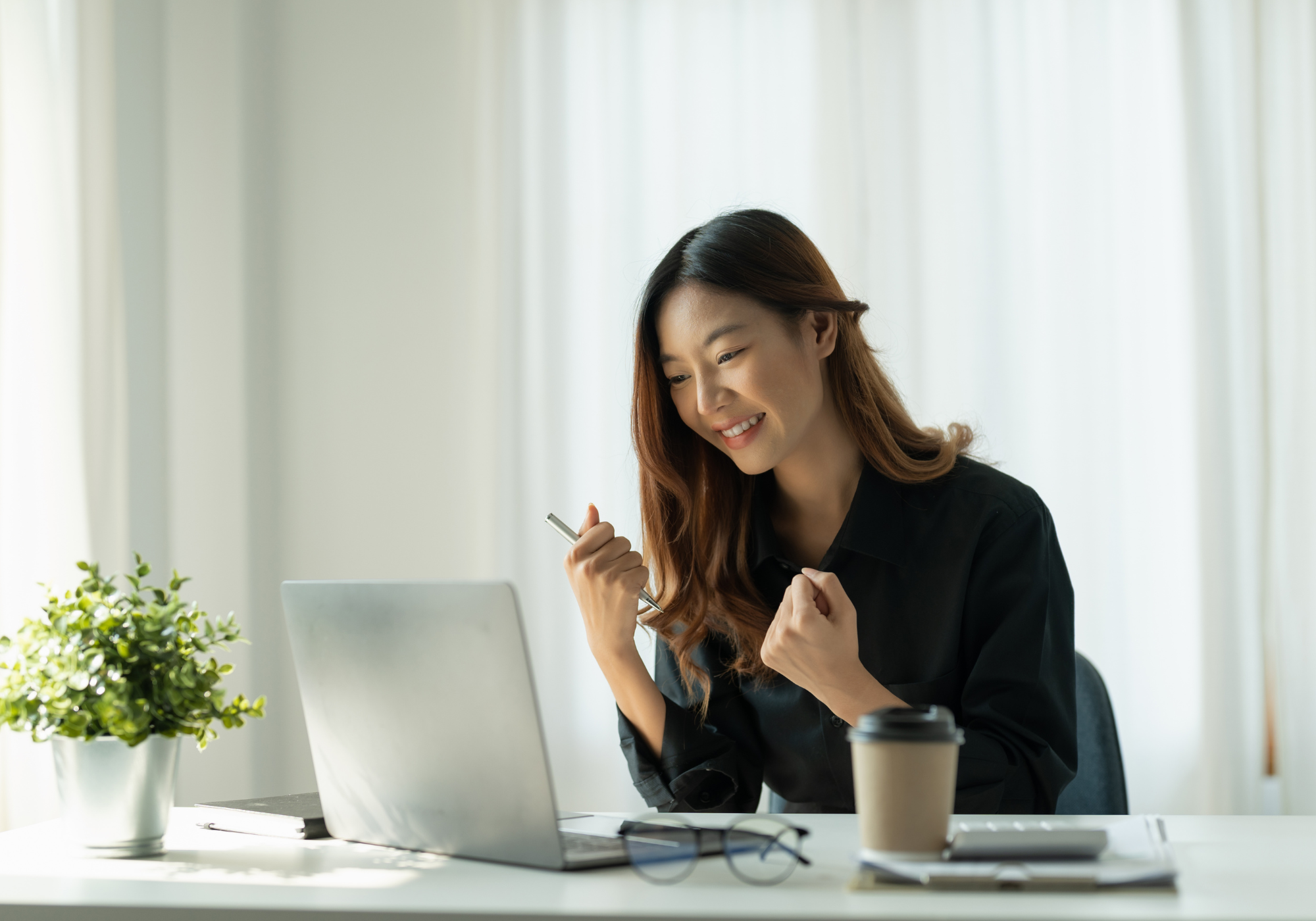 happy woman sitting at desk looking at laptop