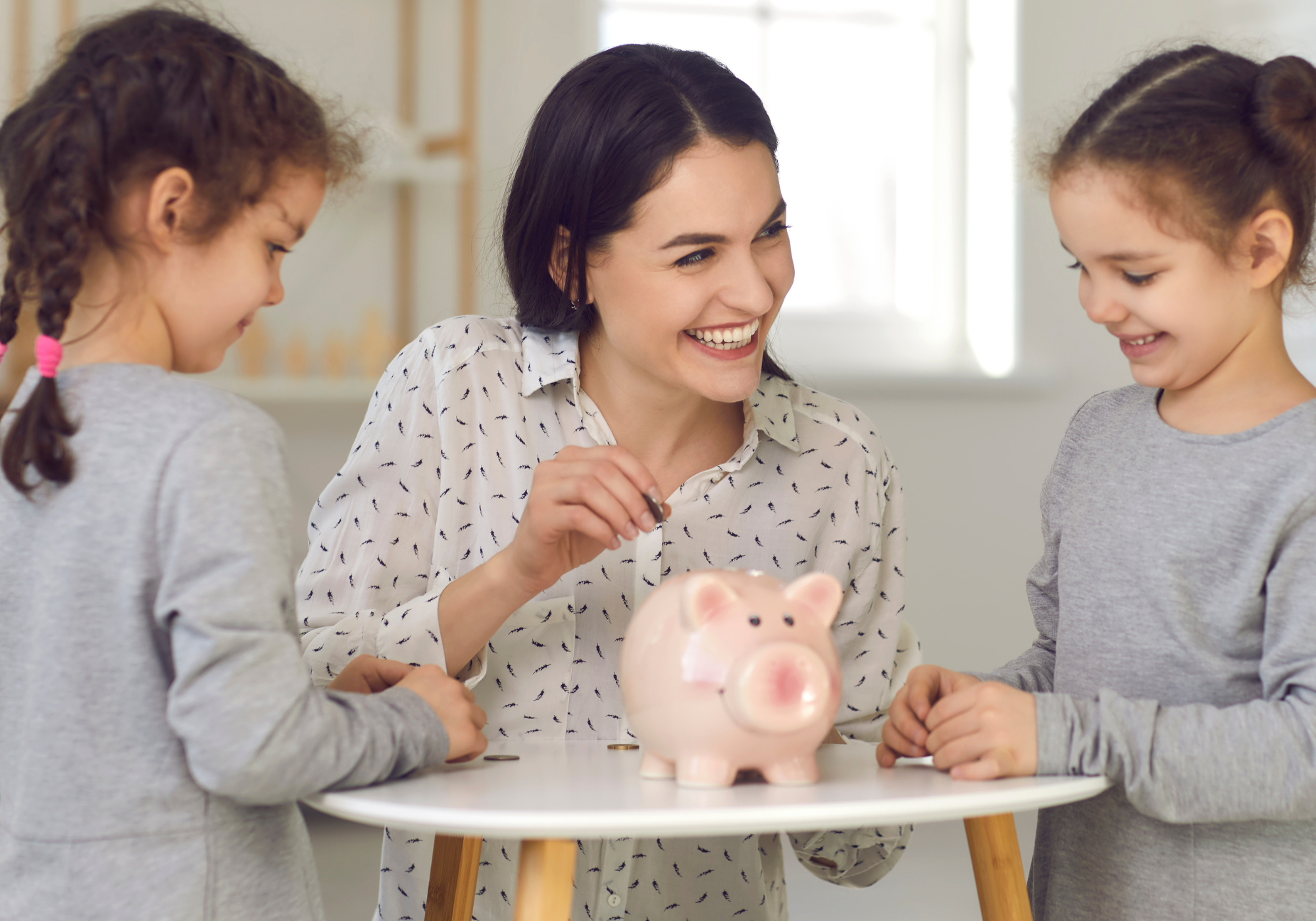 mom teaching young daughters how to save money