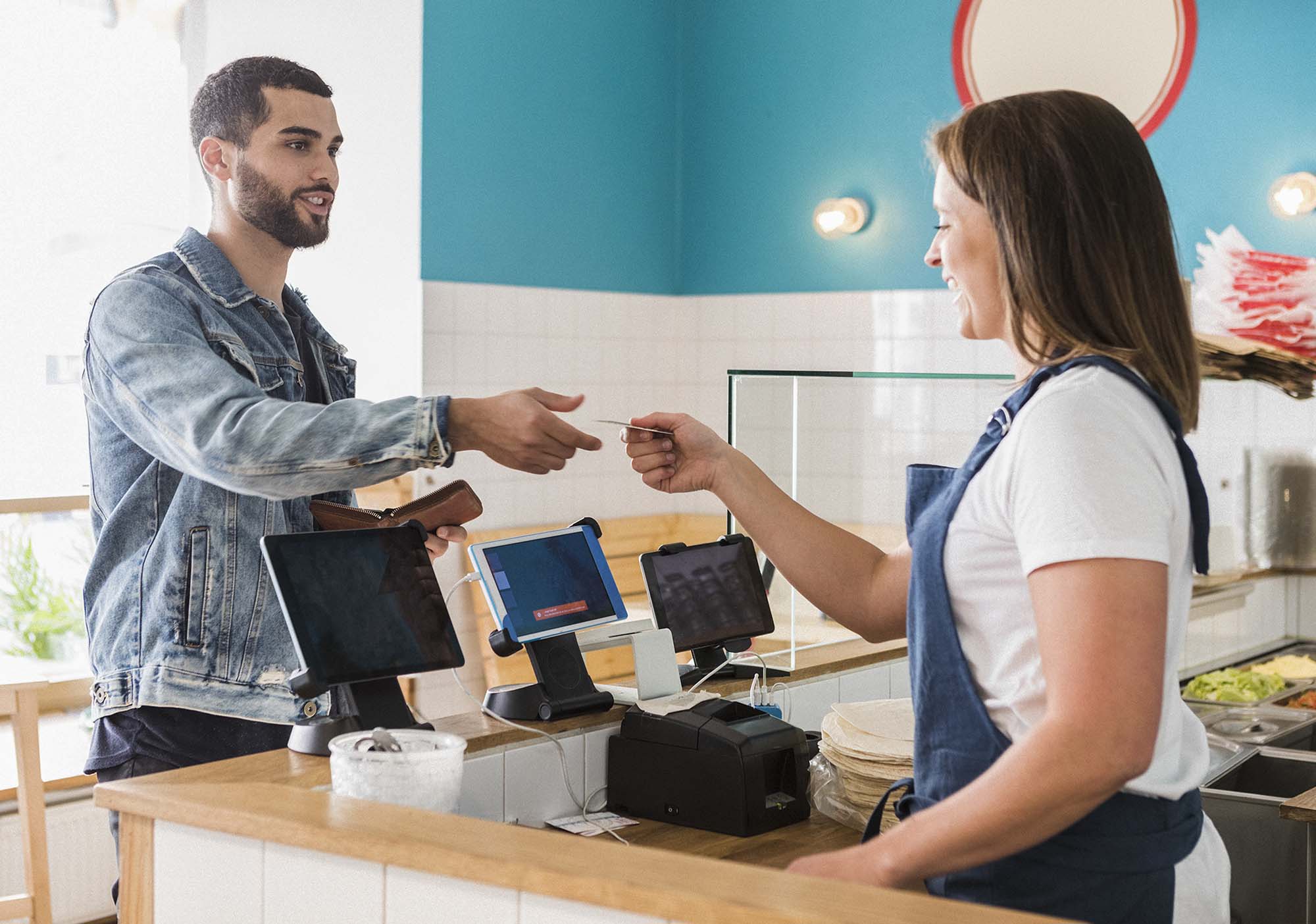 A man at a restaurant, retrieving his The Police Credit Union credit card from the cashier. 