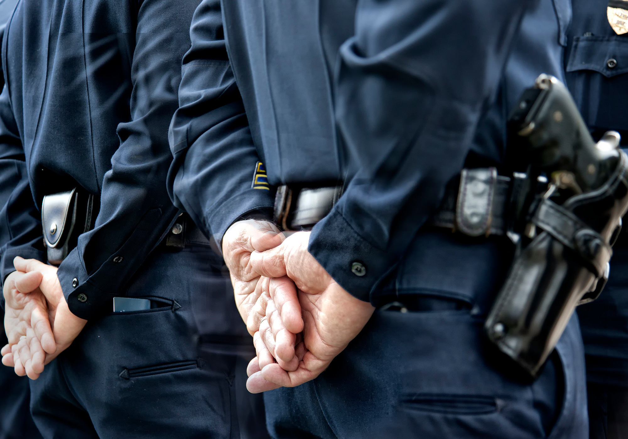 Police officers standing still with hands behind their back.