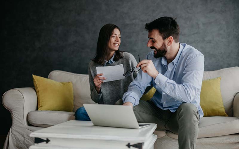 couple sitting on sofa looking at laptop