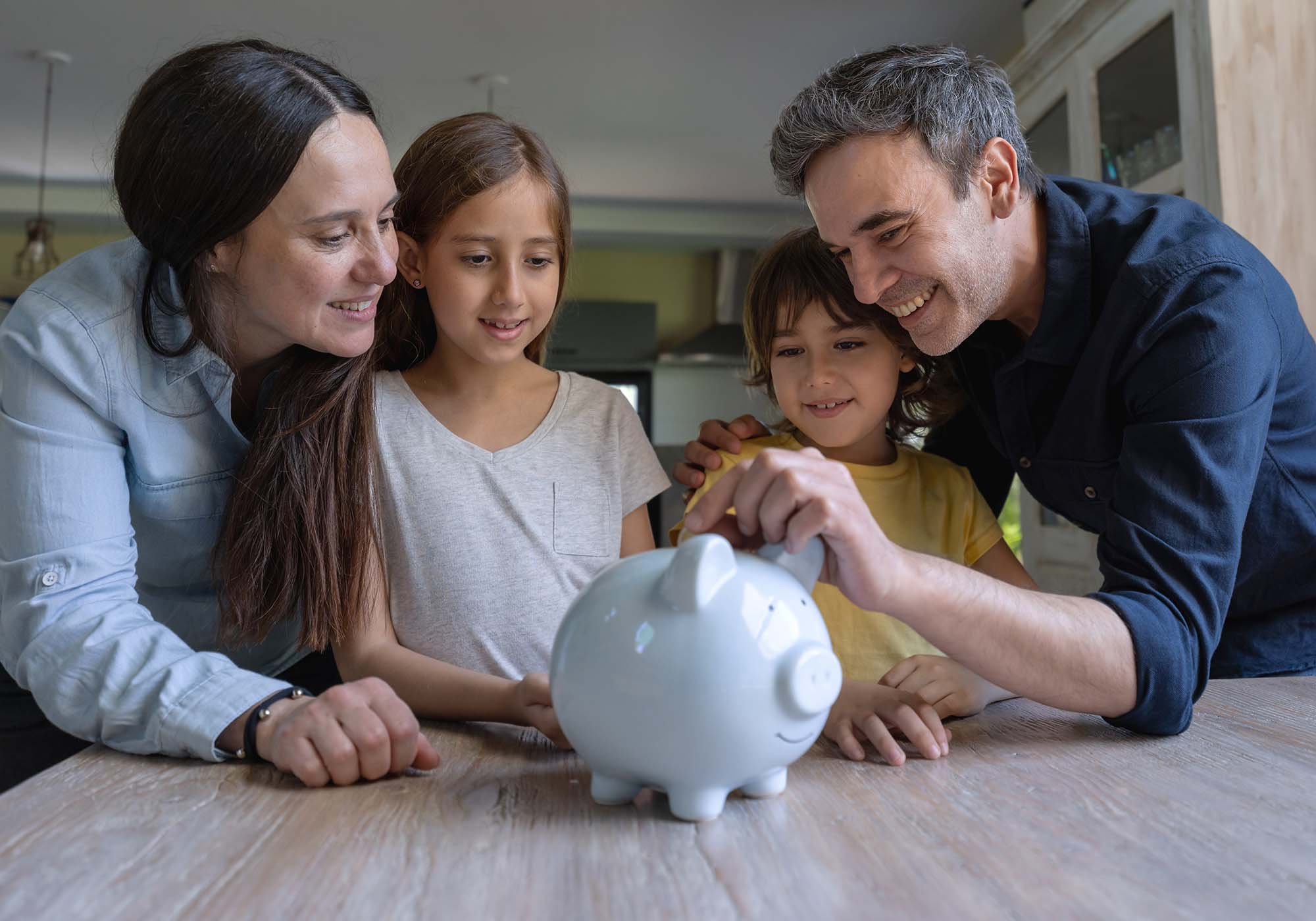 mom, dad and two children putting money in piggy bank