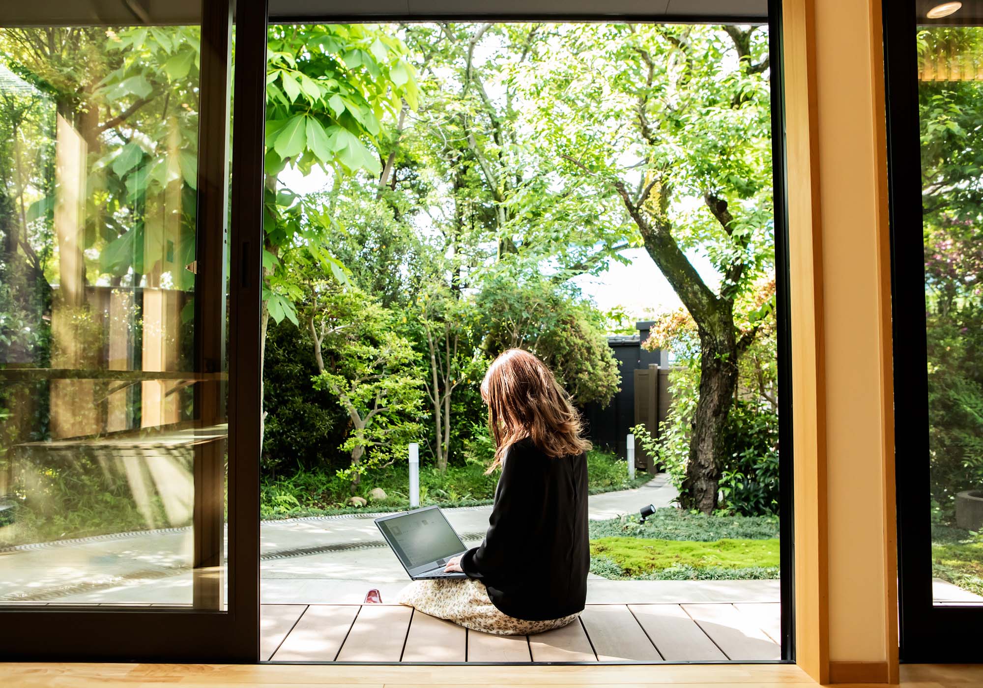 A woman sitting outside her house while looking at her laptop. 