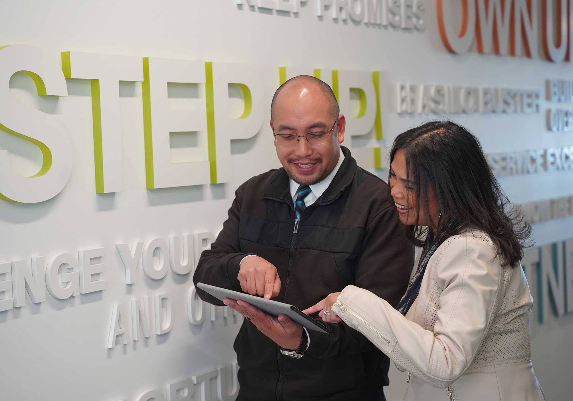 A man and woman looking at an iPad.